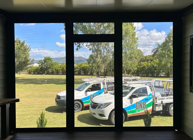 GNB utes parked on the grass, seen through a security screen
