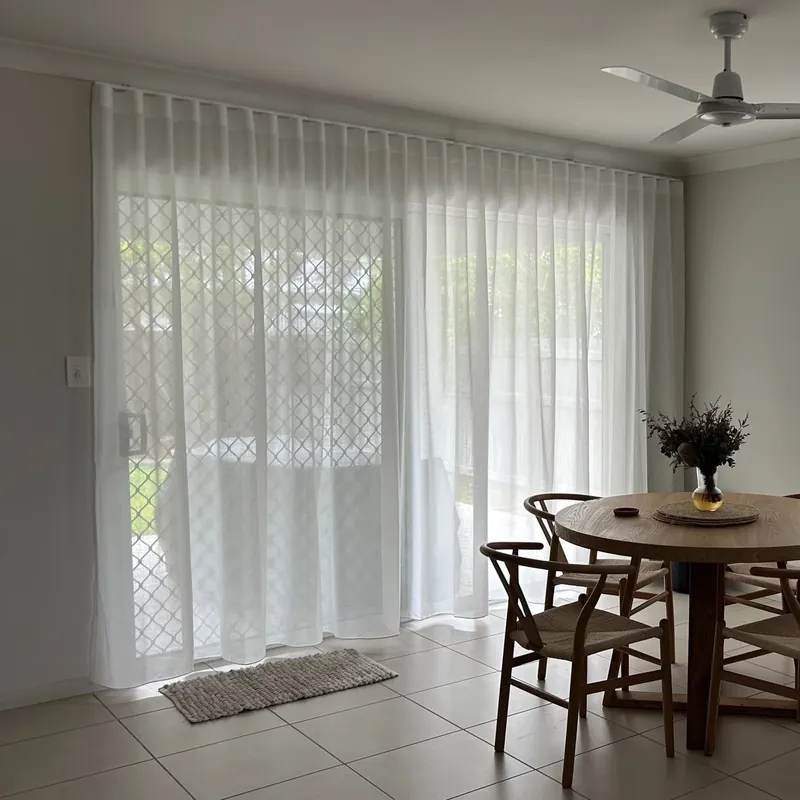 Sheer S-Fold curtains across sliding doors in a dining room