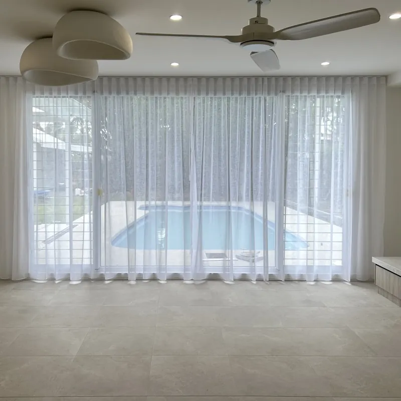 Sheer S-Fold curtains in front of a window looking out to a pool